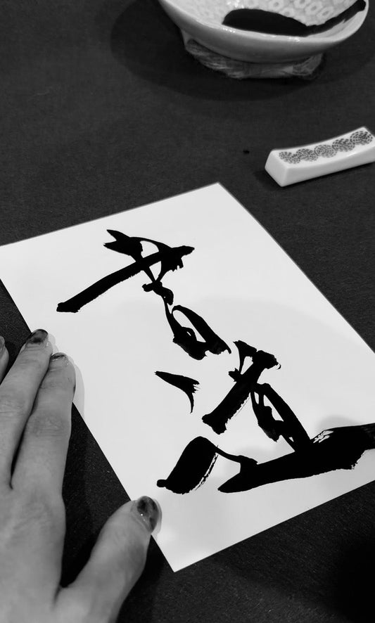 Japanese calligraphy artist Assaa holding fresh sumi ink brushwork on washi paper — BrushForma studio