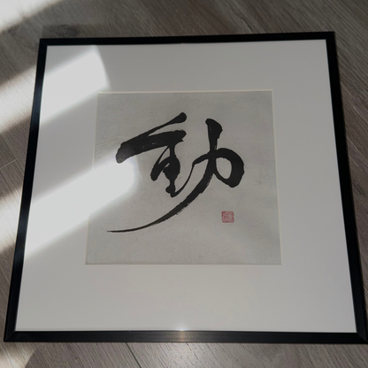 Minimalist Japanese calligraphy wall art print in a black frame on wood floor