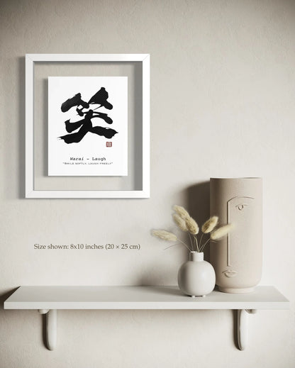 Framed artwork with black calligraphy on a beige wall above a white shelf with decorative items.