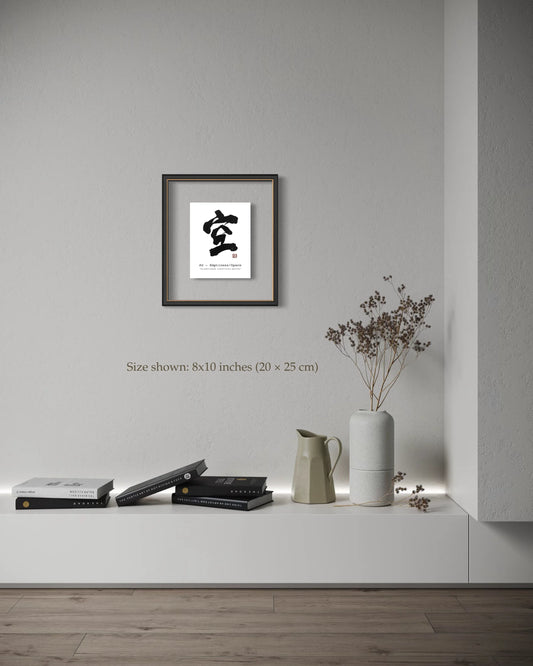 Framed artwork with a white background on a wall above a shelf with books and a vase.