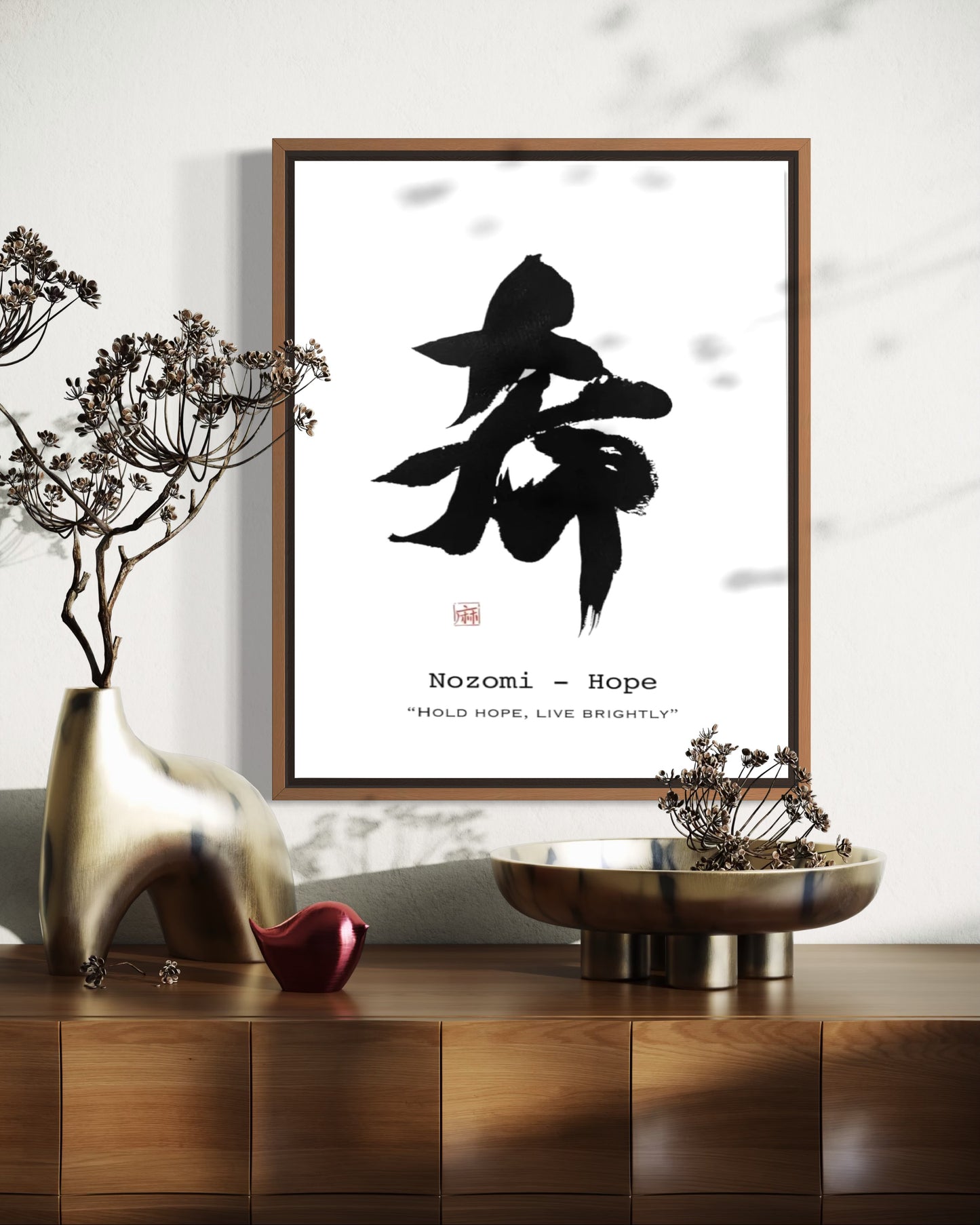 Framed artwork with black calligraphy on a white background, placed on a wooden surface with decorative items.