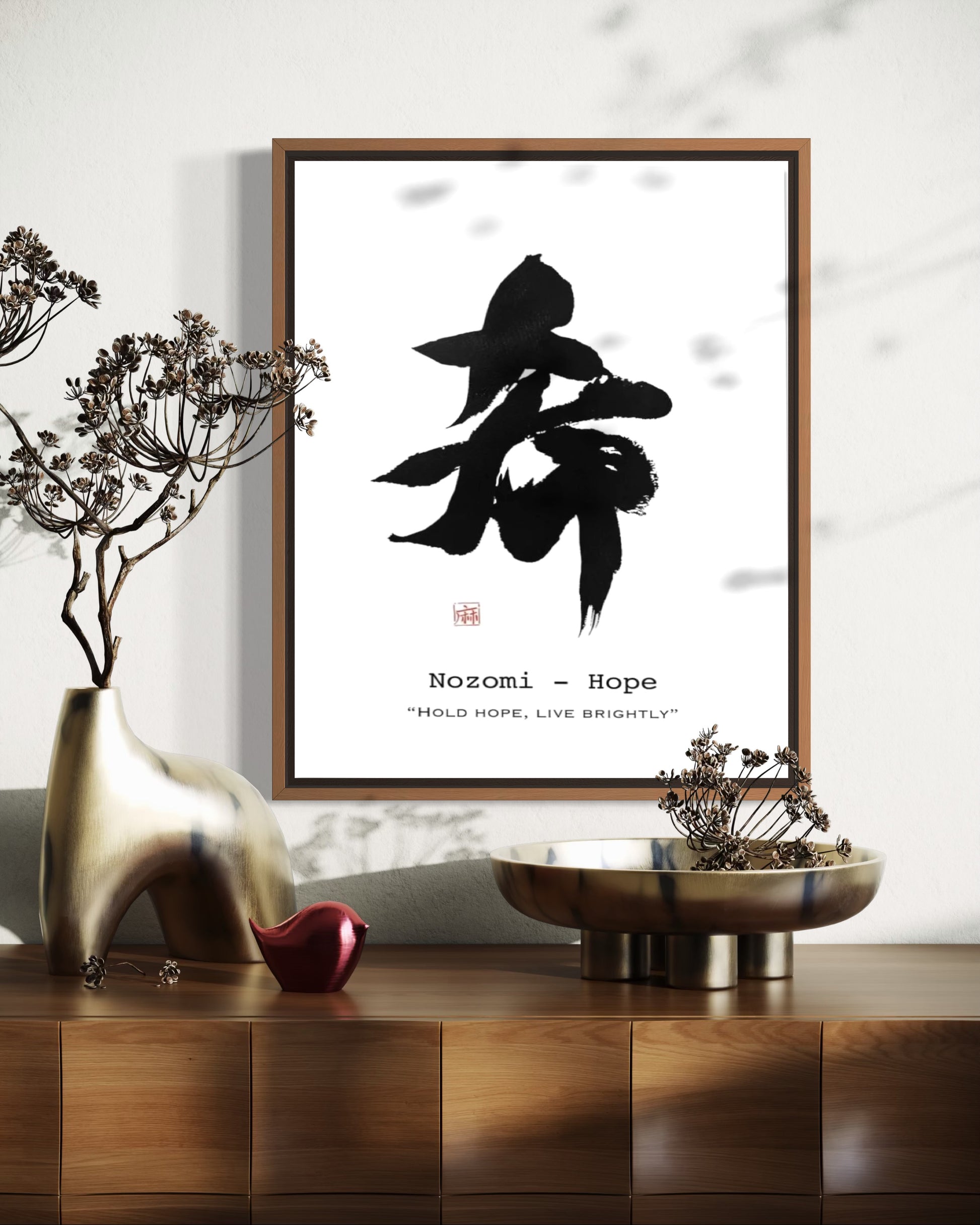 Framed artwork with black calligraphy on a white background, placed on a wooden surface with decorative items.