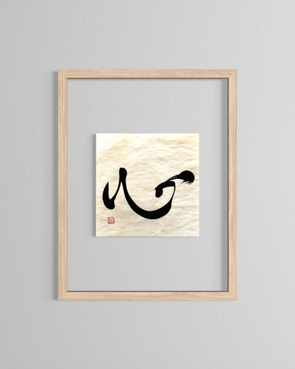 Minimalist Japanese calligraphy wall art in a light wood frame on a gray wall.