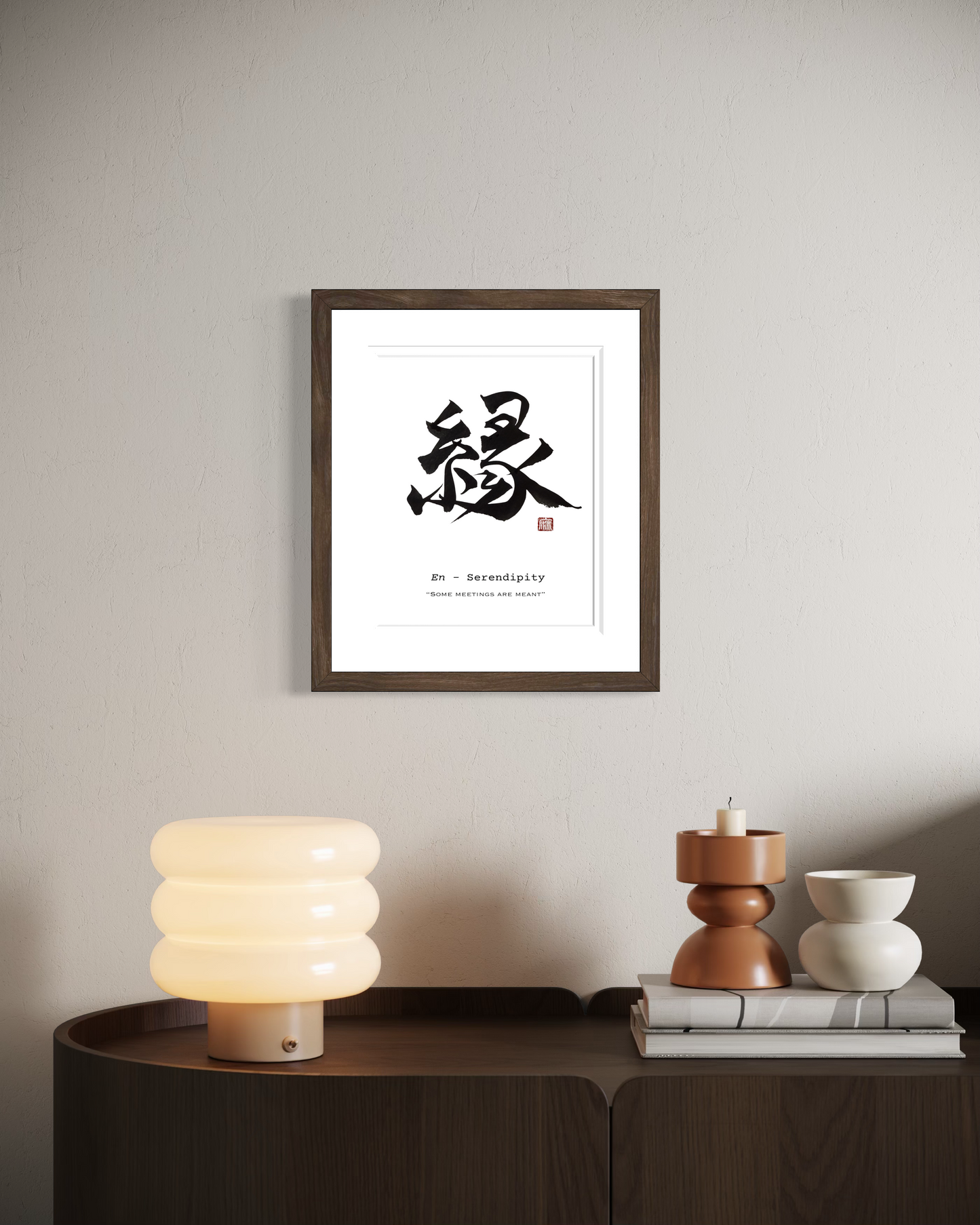 Framed artwork with a black and white design on a wall above a side table with decorative items.