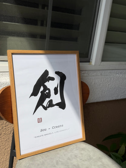 創 Sou (Create) calligraphy print in a natural wood frame, leaning by a sunny window